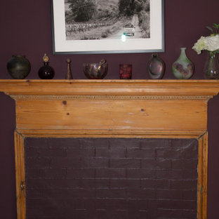 Imagen de dormitorio principal, de estilo americano, grande, con paredes púrpuras, suelo de madera oscura, chimenea tradicional, marco de chimenea de ladrillo y suelo marrón