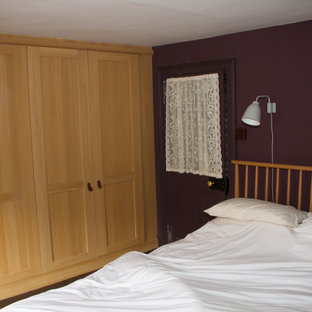 Diseño de dormitorio principal, de estilo americano, grande, con paredes púrpuras, suelo de madera oscura, chimenea tradicional, marco de chimenea de ladrillo y suelo marrón