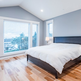 Modelo de dormitorio principal y abovedado, moderno, grande, con paredes blancas, suelo de madera clara y suelo amarillo