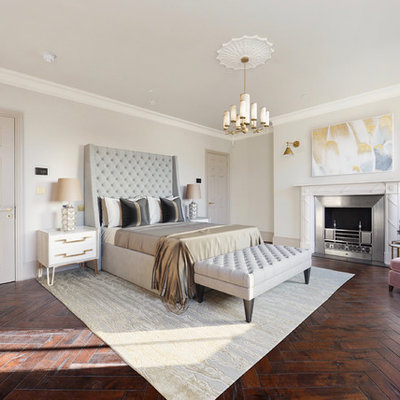 Example of a trendy master dark wood floor bedroom design in London with beige walls, a standard fireplace and a metal fireplace