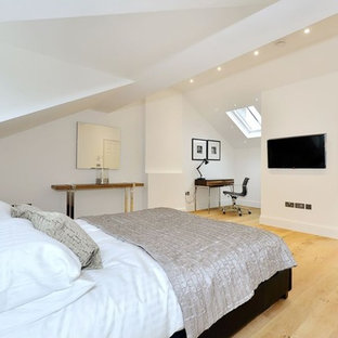 This is an example of a medium sized contemporary master bedroom in London with white walls, light hardwood flooring and beige floors.