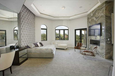 Modelo de dormitorio principal clásico renovado grande con paredes grises, moqueta, chimenea lineal, marco de chimenea de piedra y suelo beige