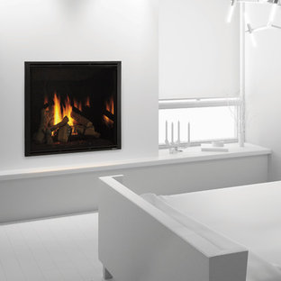 Imagen de habitación de invitados minimalista, pequeña, con paredes blancas, suelo de madera pintada, chimenea tradicional, marco de chimenea de yeso y suelo blanco