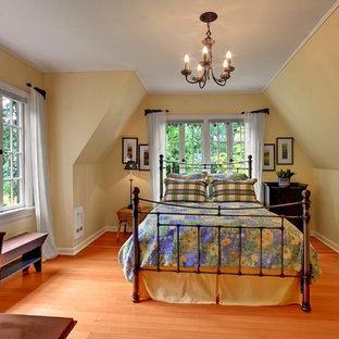 Mittelgroßes Landhausstil Schlafzimmer mit braunem Holzboden, gelber Wandfarbe und orangem Boden in Seattle