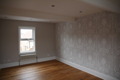 Ejemplo de dormitorio principal contemporáneo de tamaño medio sin chimenea con paredes grises, suelo de madera en tonos medios y suelo marrón