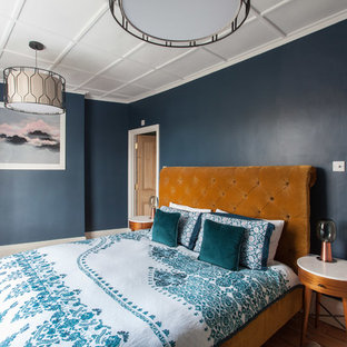This is an example of an eclectic bedroom in London with blue walls, medium hardwood flooring and brown floors.