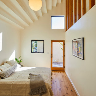 Modelo de dormitorio actual con paredes blancas, suelo de madera en tonos medios y suelo marrón