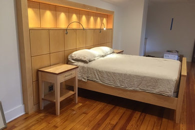 Imagen de dormitorio principal actual sin chimenea con paredes blancas y suelo de madera clara
