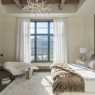 Diseño de dormitorio principal, rural, con paredes beige, suelo de madera oscura, chimenea tradicional y marco de chimenea de metal