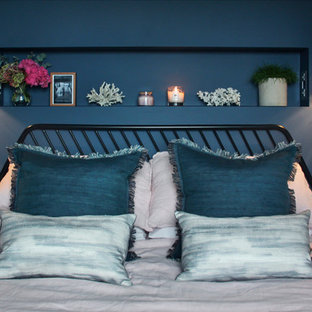 Modelo de dormitorio principal, actual, de tamaño medio, con paredes azules, suelo de madera oscura y suelo marrón