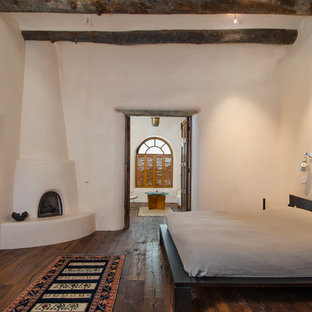 Foto de dormitorio principal, de estilo americano, grande, con paredes blancas, suelo de madera en tonos medios, chimenea de esquina y marco de chimenea de yeso