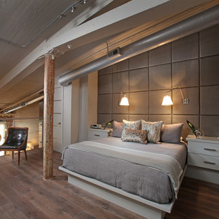 Diseño de dormitorio tipo loft, industrial, de tamaño medio, sin chimenea, con suelo de madera en tonos medios y paredes blancas