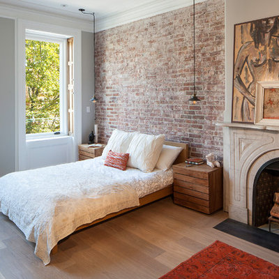 Example of a transitional master light wood floor bedroom design in New York with gray walls and a standard fireplace