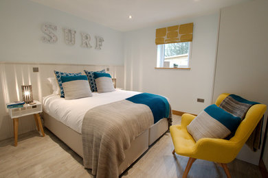 Design ideas for a medium sized coastal guest bedroom in Cornwall with blue walls, light hardwood flooring and grey floors.