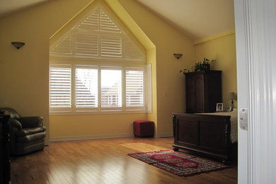 Large elegant master light wood floor and brown floor bedroom photo in Toronto with yellow walls