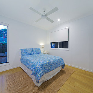 Imagen de habitación de invitados moderna, de tamaño medio, con paredes blancas, suelo de madera clara y suelo verde