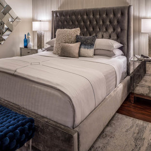 Modelo de dormitorio principal, contemporáneo, grande, con paredes blancas, suelo laminado, chimenea de esquina, marco de chimenea de baldosas y/o azulejos y suelo marrón