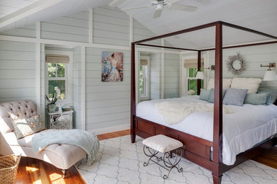Imagen de dormitorio principal costero grande sin chimenea con paredes verdes, suelo de madera en tonos medios y suelo marrón