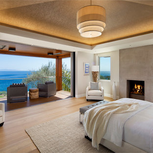 Idées déco pour une grand chambre parentale contemporaine avec un mur blanc, un sol en bois clair, une cheminée standard et un manteau de cheminée en béton.