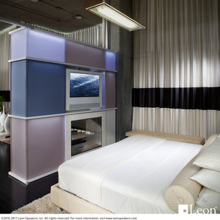 Modelo de dormitorio tipo loft, contemporáneo, pequeño, con suelo de madera oscura y chimenea de doble cara