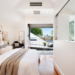 This is an example of a contemporary bedroom in Sydney with white walls, medium hardwood floors and brown floor.