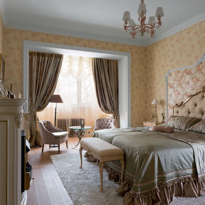 Example of a mid-sized classic medium tone wood floor bedroom design in Other with beige walls and a standard fireplace