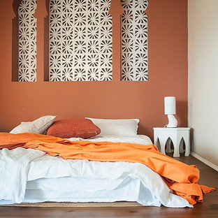 Modelo de dormitorio principal, de estilo zen, de tamaño medio, con parades naranjas y suelo de madera clara