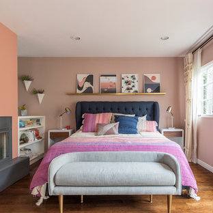 Ispirazione per una camera matrimoniale classica con pareti rosa, pavimento in legno massello medio, camino ad angolo, cornice del camino in intonaco e pavimento marrone