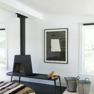 Mittelgroßes Mid-Century Hauptschlafzimmer mit weißer Wandfarbe, gebeiztem Holzboden und Kaminofen in New York