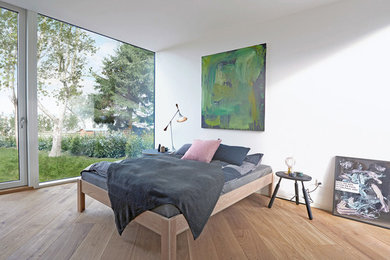 Ejemplo de dormitorio principal escandinavo de tamaño medio sin chimenea con paredes blancas y suelo de madera clara