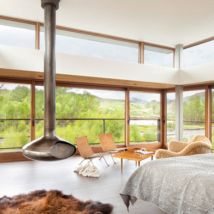 Modelo de dormitorio moderno con suelo de madera clara y estufa de leña