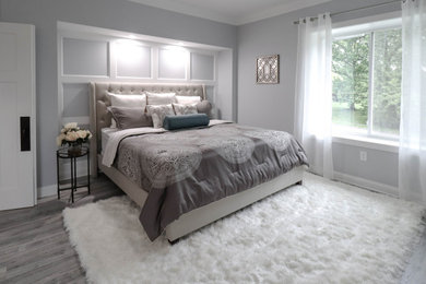 Diseño de dormitorio principal clásico renovado grande con paredes grises, suelo laminado, todas las chimeneas, marco de chimenea de baldosas y/o azulejos y suelo gris