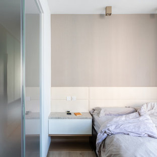 Imagen de dormitorio principal, minimalista, pequeño, sin chimenea, con paredes multicolor, suelo de piedra caliza y suelo marrón