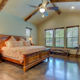 Foto de dormitorio principal, abovedado y madera, rústico, de tamaño medio, madera, con paredes beige, suelo de cemento, chimenea tradicional, marco de chimenea de piedra, suelo negro y madera