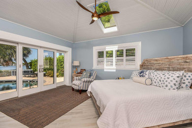 タンパにある中くらいなビーチスタイルのおしゃれな主寝室 (青い壁、セラミックタイルの床、三角天井)