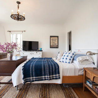 Idées déco pour une chambre parentale méditerranéenne avec un mur blanc, un sol en bois foncé, une cheminée d'angle et un manteau de cheminée en pierre.