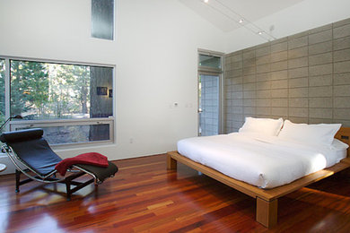Example of a trendy loft-style medium tone wood floor bedroom design in Other with white walls