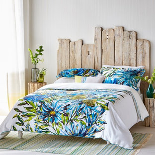 Immagine di una camera da letto tropicale con pareti bianche, pavimento in legno verniciato e pavimento bianco