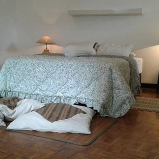 Ejemplo de dormitorio tipo loft, retro, grande, sin chimenea, con paredes blancas, suelo de contrachapado y suelo marrón