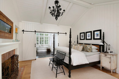 Example of a mid-sized cottage guest light wood floor and brown floor bedroom design in San Francisco with white walls, a standard fireplace and a brick fireplace