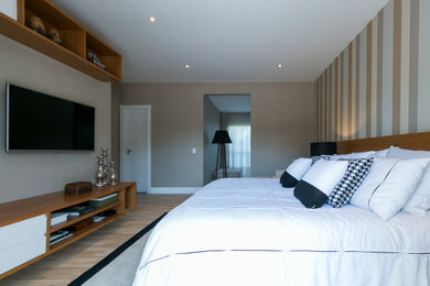 Modelo de dormitorio principal retro de tamaño medio con paredes beige y suelo de madera clara