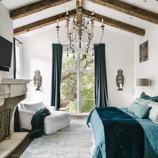 Cette photo montre une chambre parentale méditerranéenne avec un mur blanc, un sol en bois foncé et une cheminée standard.