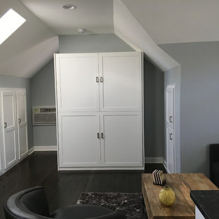 Modelo de dormitorio tipo loft, tradicional renovado, pequeño, con paredes grises, suelo de madera oscura, chimenea tradicional y marco de chimenea de metal