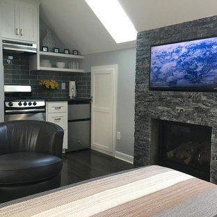 Photo of a small transitional bedroom in Minneapolis with grey walls, dark hardwood floors, a standard fireplace, a stone fireplace surround and black floor.