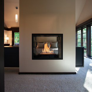 Imagen de dormitorio principal, minimalista, grande, con paredes blancas, moqueta y chimenea de doble cara