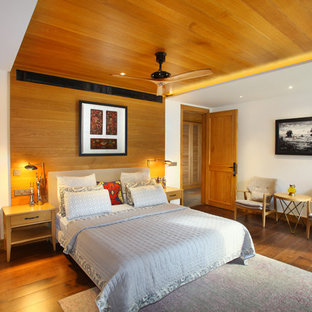 Foto de dormitorio actual con paredes blancas, suelo de madera en tonos medios y suelo marrón
