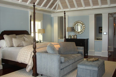 Modelo de dormitorio principal costero grande con paredes azules y suelo de madera oscura