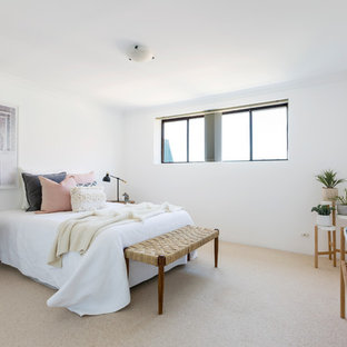 This is an example of a beach style bedroom in Sydney with white walls, carpet and beige floor.