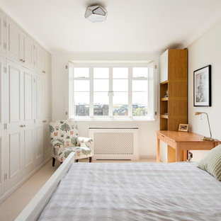 Modelo de dormitorio tradicional, de tamaño medio, con paredes beige, moqueta y suelo beige