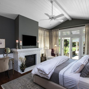 Mittelgroßes Klassisches Hauptschlafzimmer mit grauer Wandfarbe, dunklem Holzboden, Kamin und Kaminumrandung aus Backstein in Los Angeles